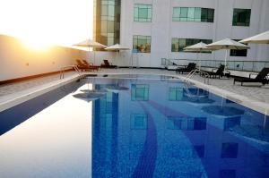 a pool with chairs and umbrellas next to a building at Lavender Hotel Al Nahda Dubai in Dubai