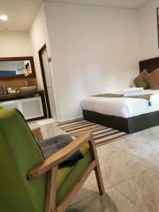 a bedroom with a bed and a green chair at The Temak Villa in Pantai Cenang