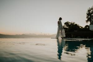 Un uomo in piedi sul bordo di un corpo d'acqua di Pefkaki Boutique Hotel Loutraki a Loutraki