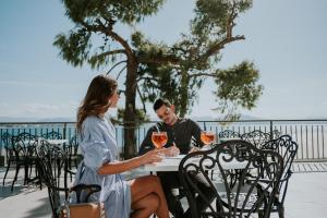 Pefkaki Boutique Hotel Loutraki في لوتراكي: رجل وامرأة يجلسان على طاولة مع كؤوس للنبيذ