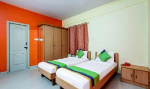 two beds in a room with orange walls at Itsy By Treebo - Jasmine in Mysore