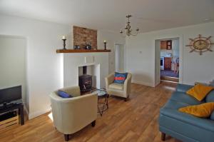 a living room with a couch and chairs and a fireplace at Cottage at Youghal Bridge in DʼLoughtane Cross Roads