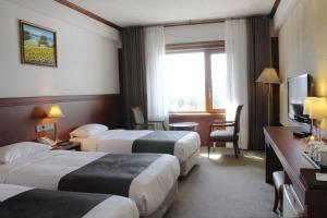 a hotel room with three beds and a television at Commodore Hotel Gyeongju in Gyeongju