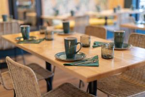 a wooden table with green cups and plates on it at Hôtel Saint-Julien in Angers +43 photos