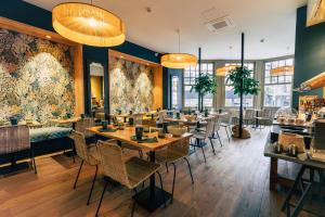 a restaurant with wooden tables and chairs and a large mural at Hôtel Saint-Julien in Angers