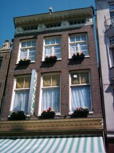 アムステルダムにあるホテル シュロダーの窓と花箱のある高いレンガ造りの建物