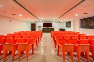 an empty lecture hall with orange chairs and a podium at Raj Residency in Hosdrug