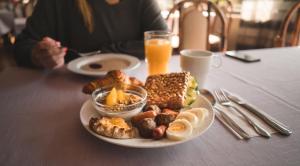 a plate of breakfast food on a table with orange juice at Revontuli Resort Cottages in Hankasalmi