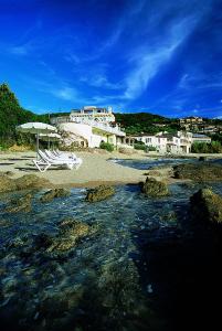 a beach with two chairs and an umbrella and water at Hotel Le Maquis in Porticcio