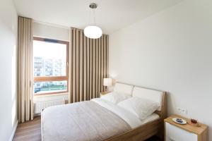 a white bedroom with a bed and a window at YOURAPART Letnica Sea Side in Gdańsk