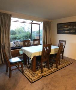 uma sala de jantar com uma mesa e cadeiras e uma janela em The Gardens' Treasure em Auckland