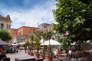 een stadsstraat met mensen aan tafels en bomen bij Hostel Villa Viva in Bregenz