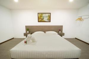a white bed with a stuffed animal sitting on it at NK Residence Sakon Nakhon in Sakon Nakhon