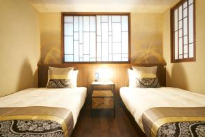 two beds in a room with two windows at Private Hotel Kanazawa SHIKI in Kanazawa