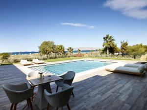 a patio with a table and chairs and a swimming pool at Pelagos Suites Hotel & Spa in Kos