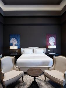 a bedroom with a large bed and two chairs at Pelagos Suites Hotel & Spa in Kos