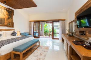 a bedroom with a large bed and a television at Bije Boutique & Gallery in Ubud