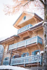 Cette grande maison en bois possède un balcon bleu. dans l'établissement La FERME des Lombardes, à Saint-Jean-de-Sixt