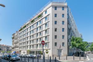 un gran edificio blanco con coches aparcados en un aparcamiento en B&B HOTEL Marseille Centre La Joliette, en Marsella