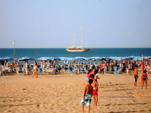 a group of people on the beach with a boat in the ocean at Baia Degli Aranci Suite & Apartments in Vieste