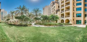 a large yard in front of a building with palm trees at Spacious family apartment on the Palm in Dubai