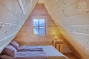 a bed in a wooden room with a window at Oaza Tatry I in Zakopane