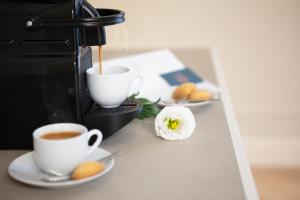 two cups of coffee on a counter with plates of food at Hotel La Caporala in Castel d'Azzano