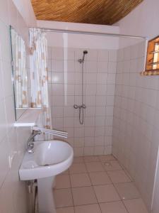 a white bathroom with a sink and a shower at le baobab de nianing in Nianing