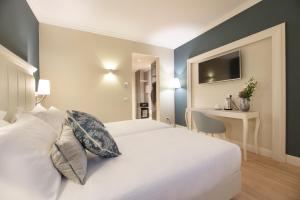 una camera con letto bianco e scrivania di Hotel La Caporala a Castel d'Azzano