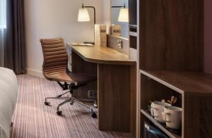 a hotel room with a desk and a chair at Leonardo London Heathrow Airport in Hillingdon