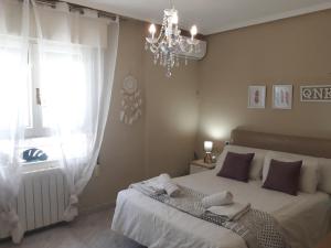 a bedroom with a bed with a chandelier and a window at Cute Home Bethlem in Cuenca