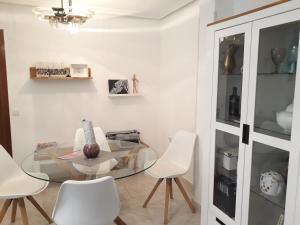 a dining room with a glass table and white chairs at Cute Home Bethlem in Cuenca