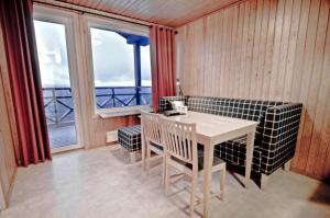 ein Esszimmer mit einem Tisch, Stühlen und einem Fenster in der Unterkunft Kåppas Cabin Village in Björkliden