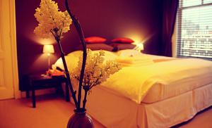 - une chambre avec un lit et un vase avec des fleurs dans l'établissement Maison Indochine, à La Haye