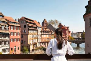 a woman standing on a bridge looking at a city at Hotel & Spa REGENT PETITE FRANCE in Strasbourg