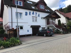 une voiture garée devant un bâtiment blanc dans l'établissement Gościniec BEATA, à Łagów