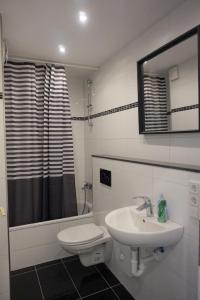 ein Badezimmer mit einem Waschbecken, einem WC und einem Spiegel in der Unterkunft Artus Hotel in Düsseldorf