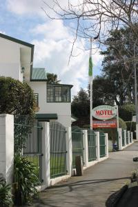 uma cerca branca em frente a uma casa com uma placa de motel em Greenlane Manor Motel em Auckland