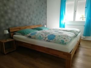 Schlafzimmer mit einem Bett mit einem Holzrahmen und blauen Vorhängen in der Unterkunft Ferienwohnungen Haus Sauer in Offenheim