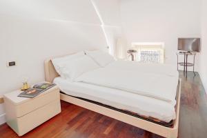 a bedroom with a white bed with a nightstand and a tv at Ex Tribunale Palazzo Bentivoglio Apartment in Ferrara