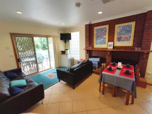 a living room with couches and a table and a fireplace at Angela's Beach Stays in Apollo Bay
