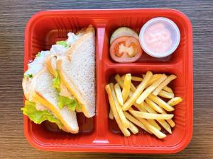ein rotes Lunchpaket mit einem Sandwich und Pommes Frites in der Unterkunft Sitio Uno Residences in Roxas City