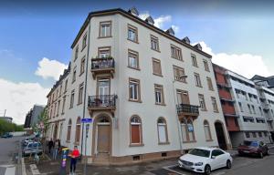 een groot wit gebouw met een auto ervoor geparkeerd bij Belles combles alsaciennes au centre de Strasbourg in Straatsburg