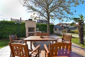 einen Holztisch und Stühle mit einem Tisch und einem Baum in der Unterkunft Apartments Valbandon 38 in Fažana