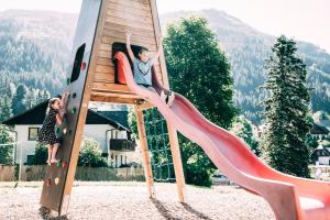 een jongen en een meisje op een glijbaan in een speeltuin bij Kinderhotel Stegerhof in Donnersbachwald