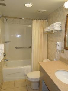 a white toilet sitting next to a bath tub in a bathroom at The Breakers Resort Inn in Virginia Beach