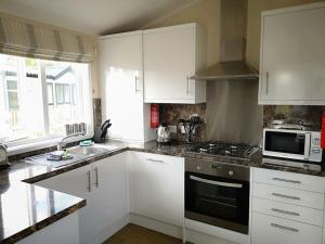 a kitchen with white cabinets and a stove top oven at Carnoustie Lodge in Wisbech