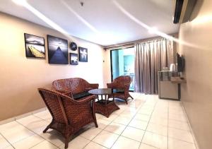 a living room with chairs and a table and a television at EM HOMESTAY(Coral Bay 3Room Apartment) in Pangkor