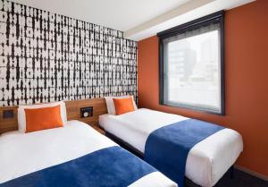 two beds in a room with orange walls and a window at the b akasaka-mitsuke in Tokyo