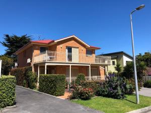 a brick house with a balcony on a street at Angela's Beach Stays in Apollo Bay